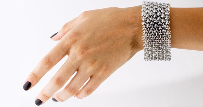 3D-printed precious metal bracelet with intricate lattice pattern worn on a wrist.