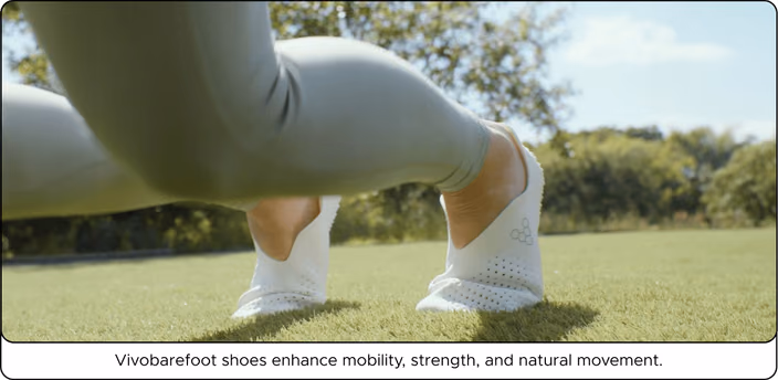 Person wearing Vivobarefoot minimalist shoes outdoors on grass, demonstrating natural foot movement and comfort