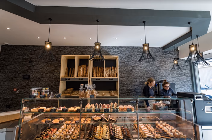 Multiple custom Shapelamp pendant lights hanging in a row above a bakery display case, demonstrating mass customization capabilities