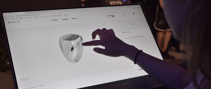 A customer touches a 3D signet ring in the Nove25 configurator on a large in-store screen.
