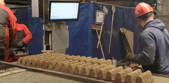 Shop floor workers positioning sound-absorbing cork material with reference to a monitor displaying placement instructions.