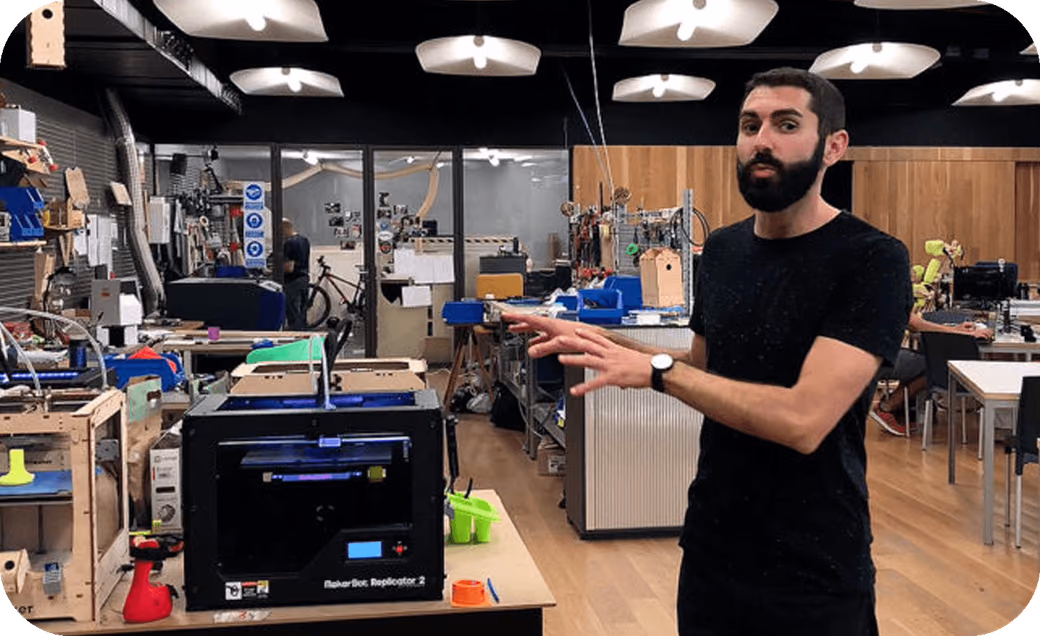 Someone presenting inside the MediaLab Prado FabLab, surrounded by 3D printers and digital fabrication equipment