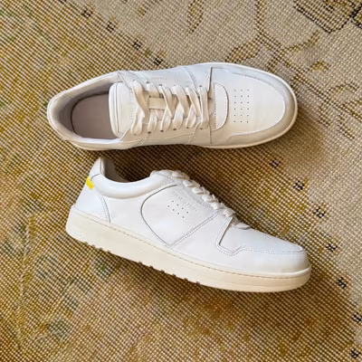 A pair of white sneakers with custom 3D-printed soles on a rug